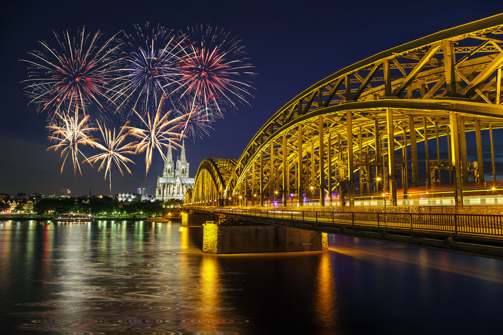 Ville de Rhénan le soir pour le réveillon avec un pont lumineux, une cathédrale en arrière plan et un feu d'artifices.